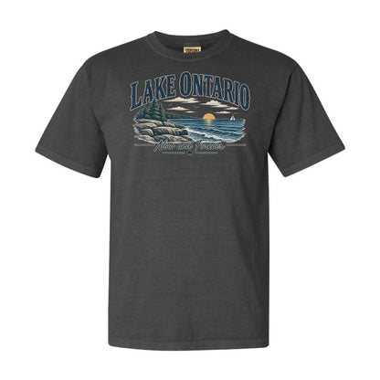 A dark charcoal gray short-sleeve t-shirt with a graphic print of Lake Ontario, featuring a scenic sunset over water with rocks and pine trees, and the text 'LAKE ONTARIO' and 'NORTH OF ENGLAND'.